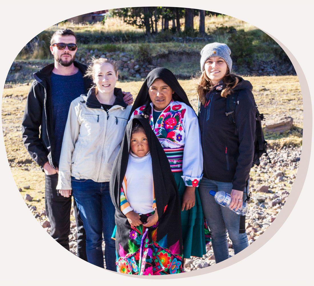 Three tourists are pictured with their Lake Titicaca local homestay hosts. They are all dressed for cold weather