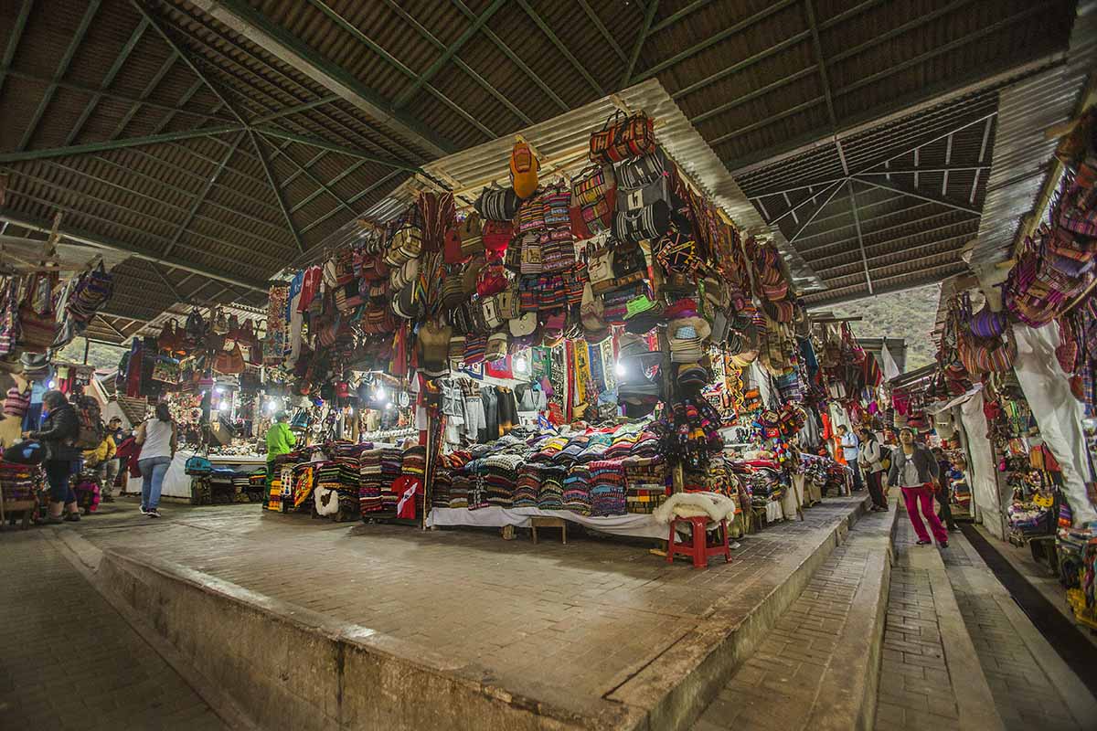 Stalls at the artisanal market in Aguas Calientes with piles of souvenirs for sale. 