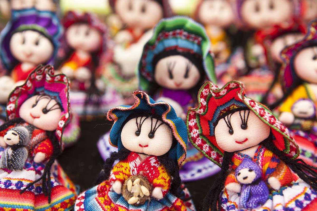 Andean dolls wearing traditional woven skirts, shawls, and hats with black bead eyes.