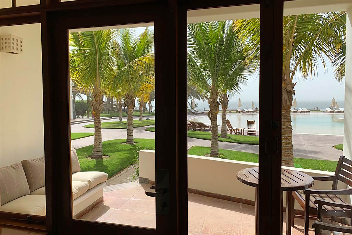 Looking out at the pool and palm trees from a ground-level room at Hacienda Paracas Hotel. 