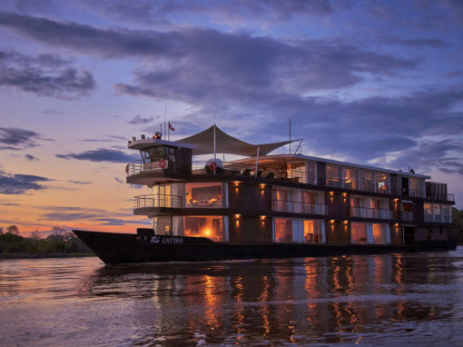 An amazon cruise slowly floats up river at sunset.
