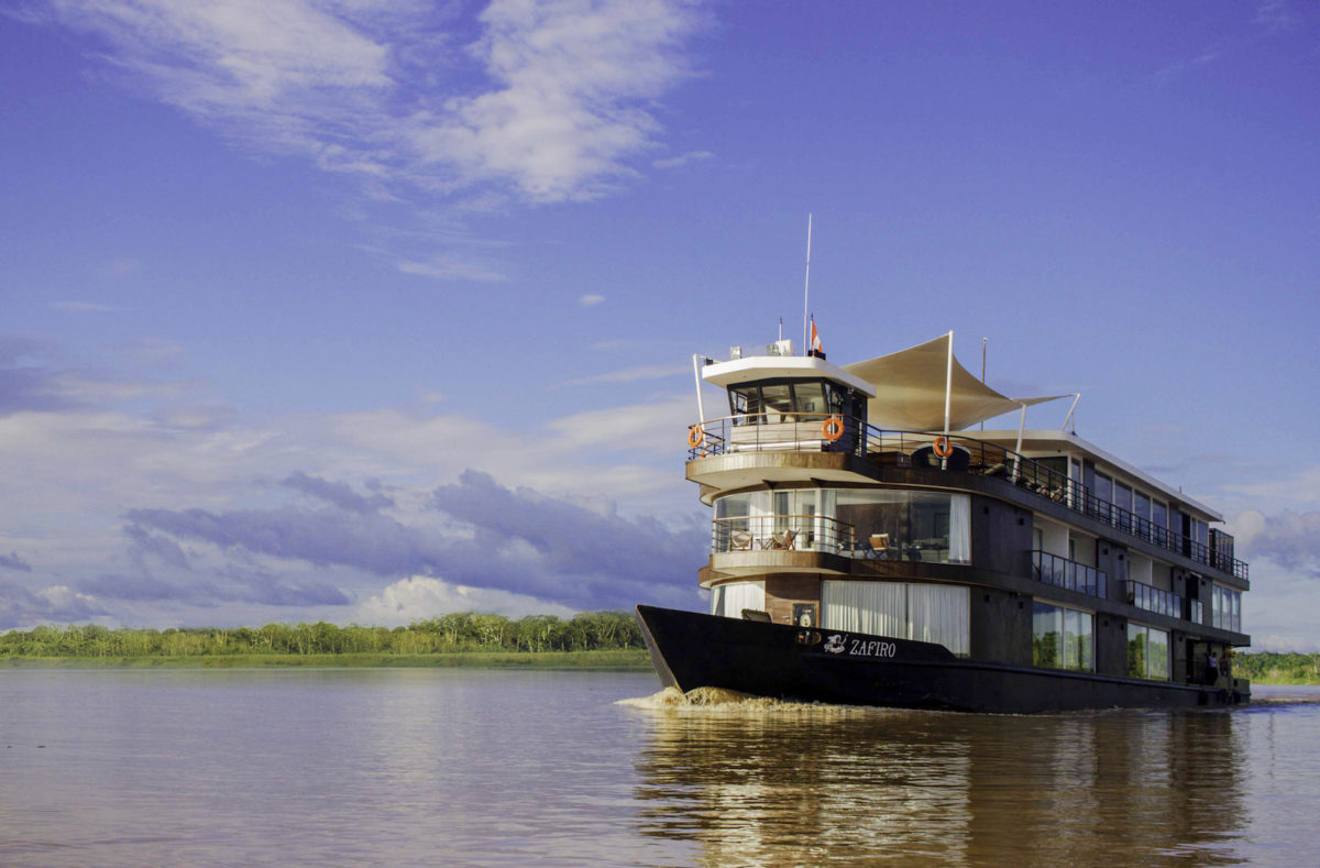 An amazon cruise slowly floats up river on a sunny day. 