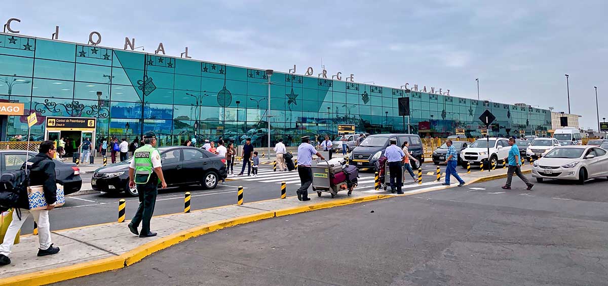 Many people walking and cars driving in front of the Lima airport.