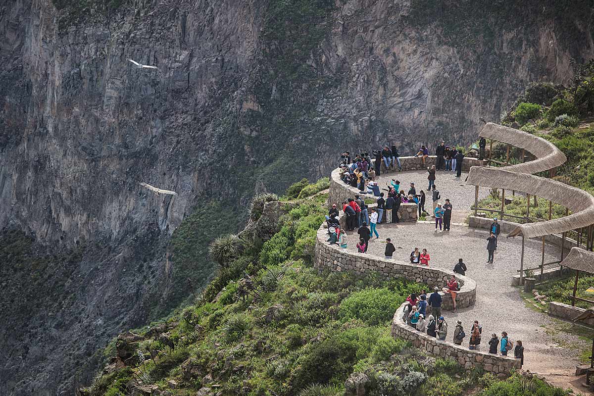 People looking out at flying condors from Mirador Cruz del Condor in Colca Canyon.