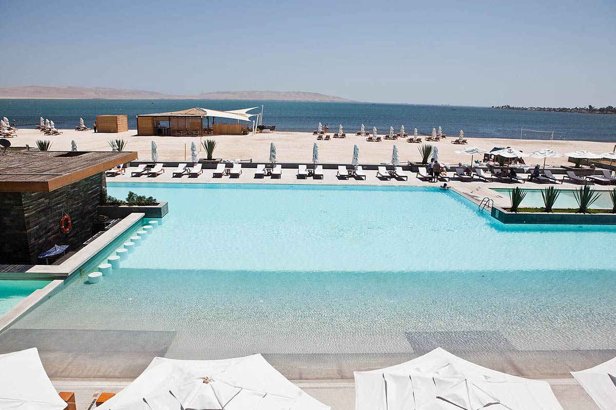 The expansive turquoise pool at the Doubletree Hilton with the Paracas Bay in the background. 