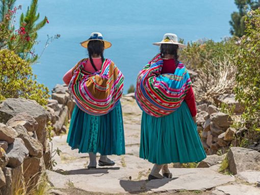 Two indigenous Quechua women in traditional clothing walking down a path to the harbor of Isla Taquile near Puno.