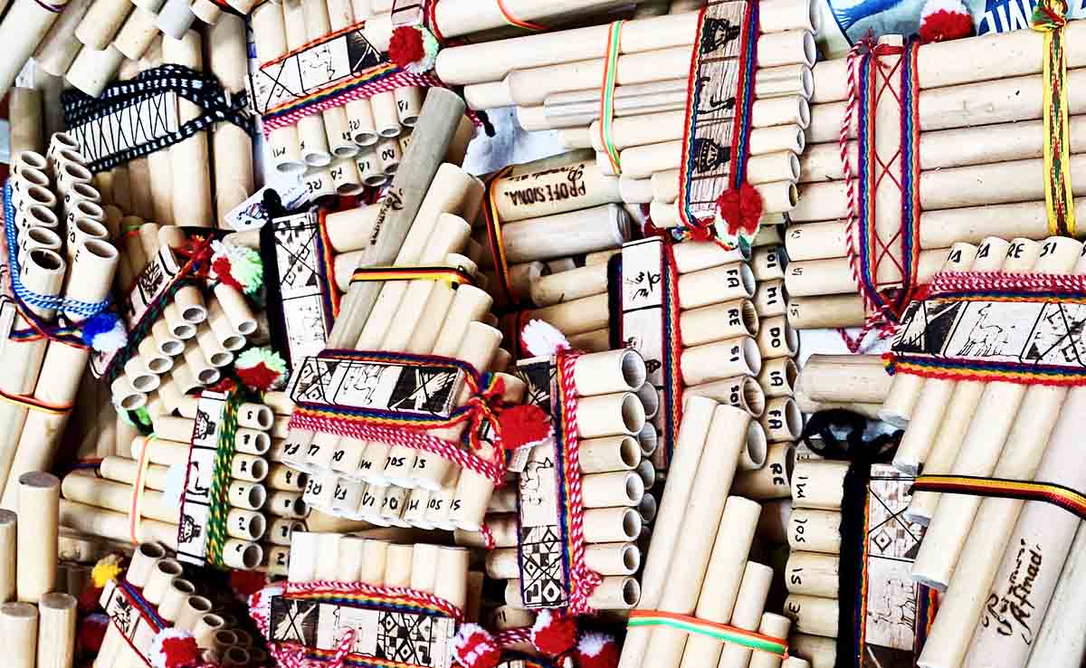 An array of Andean panpipes with different colors and bands around them.