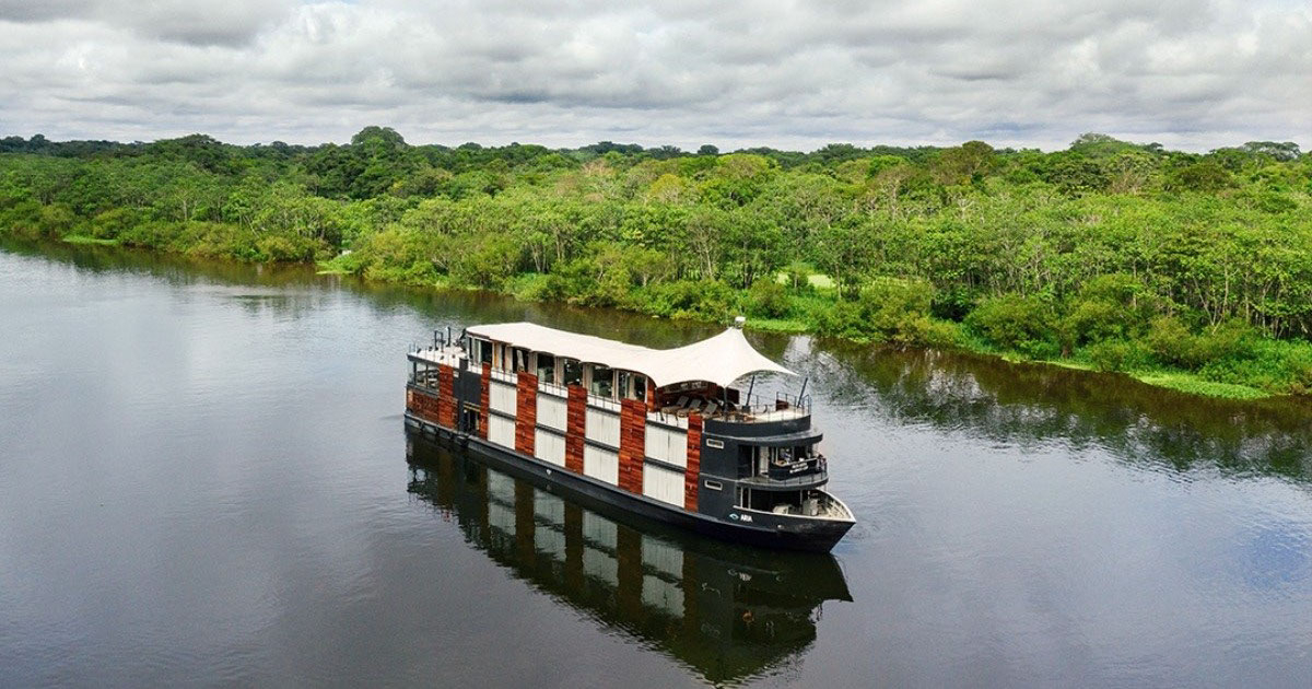 The Aria Amazon Cruise anchored off a verdant riverbank. 