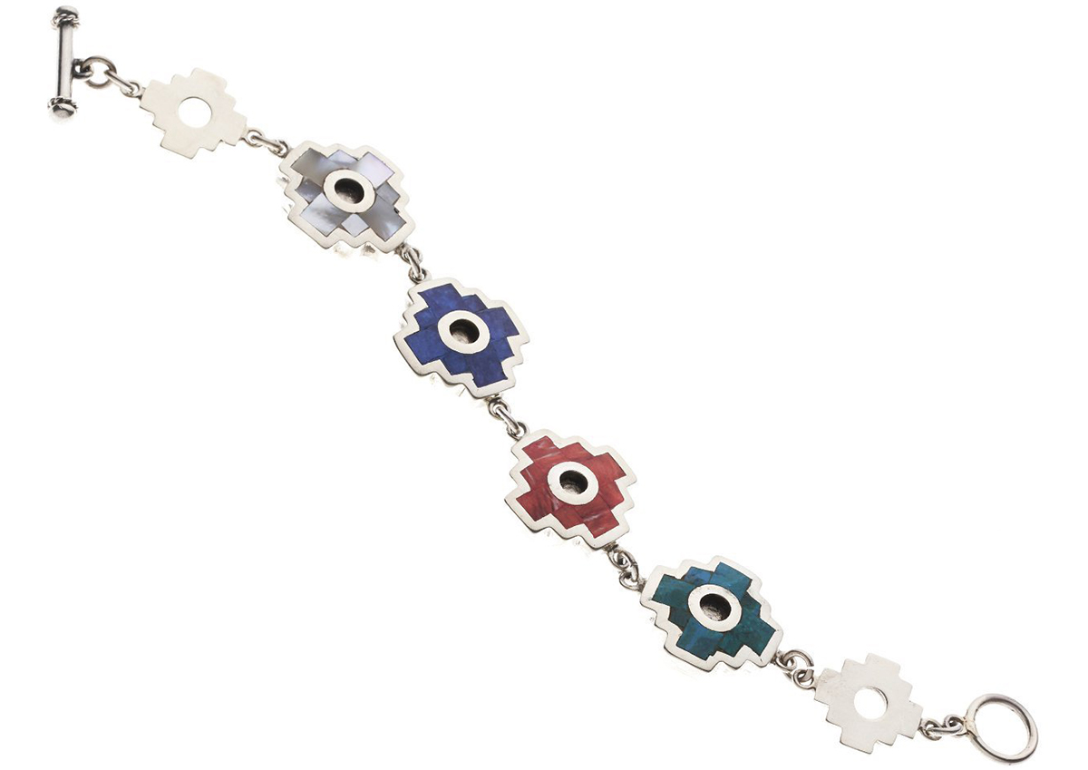 A silver chakana bracelet with gray, blue, red, and turquoise stone inlays.