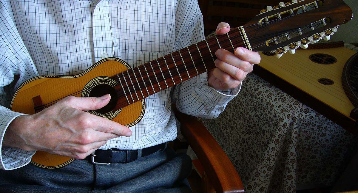 A man plays a charango, a small stringed instrument with ten strings.