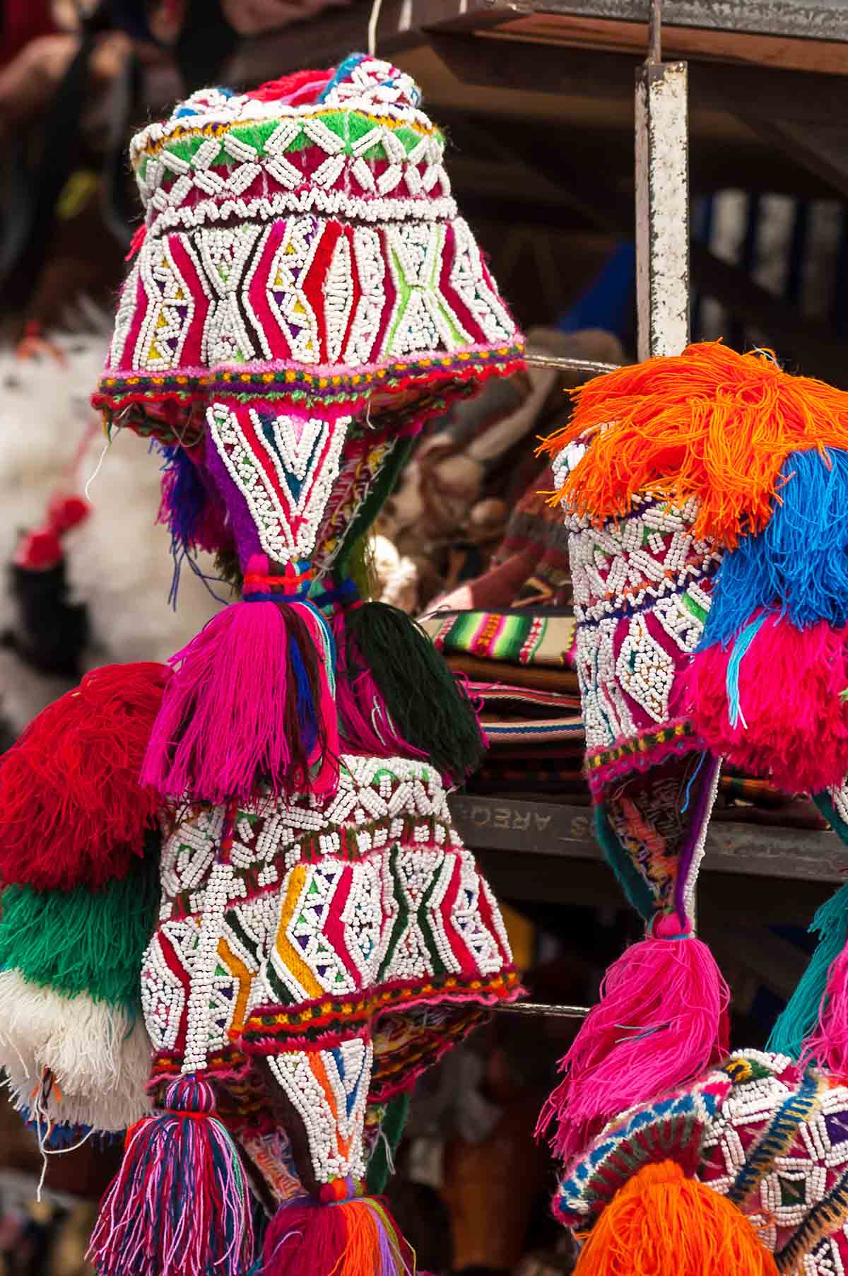 Bright red, yellow, and green chullos with white beading and tassels.