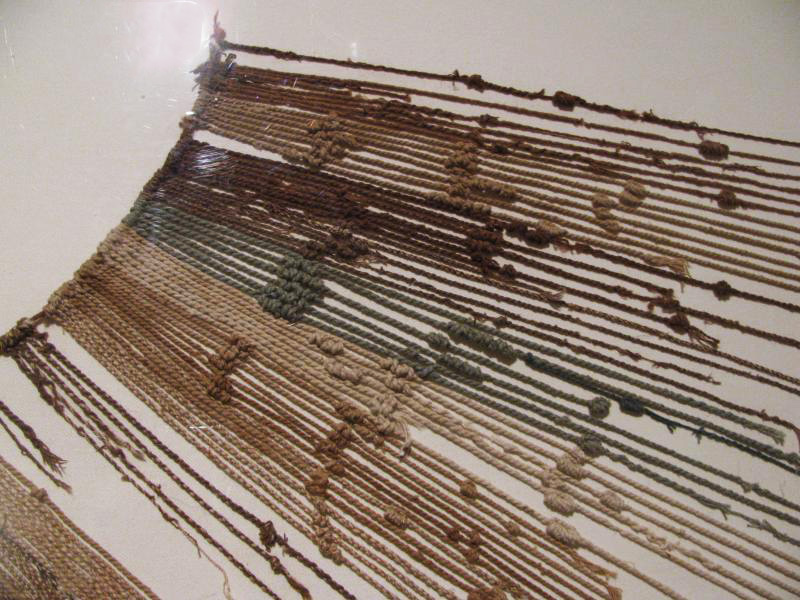 An example of a quipu made of yellow, green, and red fabric with knots used to record information.