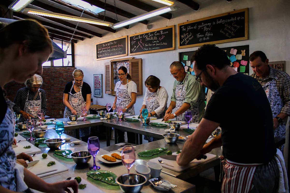 A group of tourists learning how to make ceviche in a local cooking workshop.