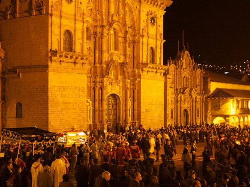 Crowds of people gathered in front of the Cusco Cathedral at night for an Easter procession.