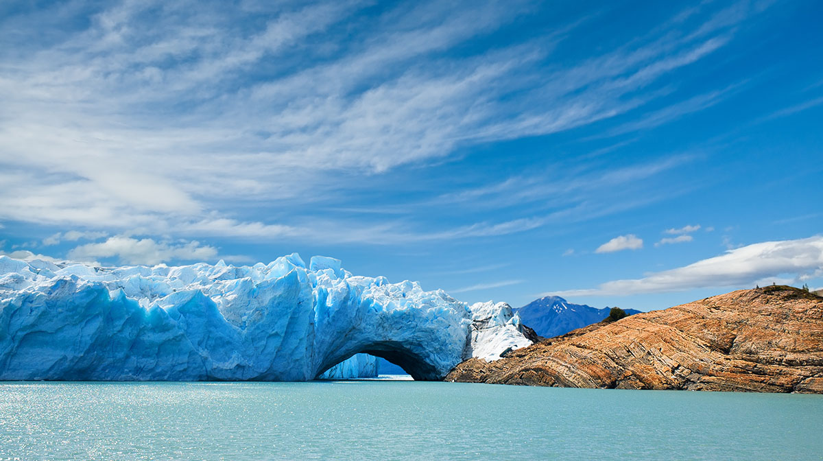 Icy blue waters surrounding white and blue glaciers under a blue sky at El Calafate.