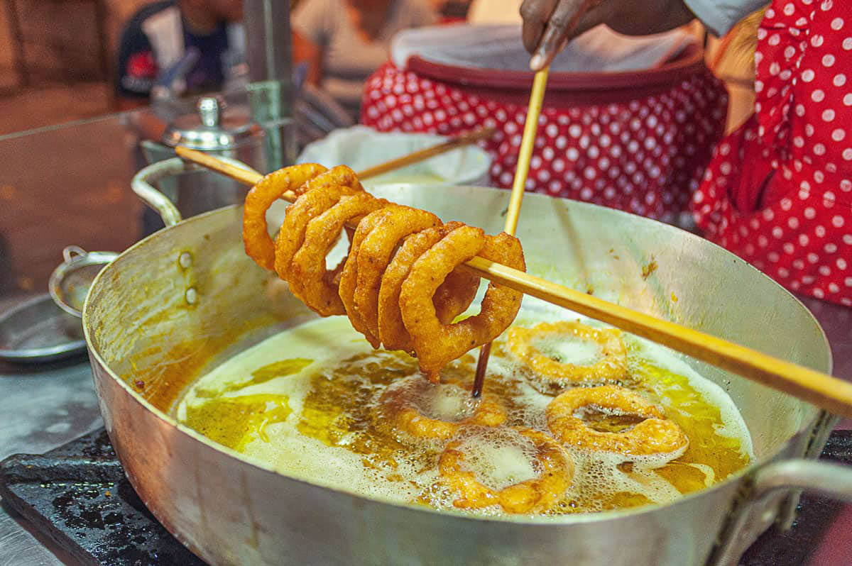 Skewer with golden brown deep fried rings of dough over boiling oil