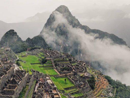 Machu Picchu and the surrounding mountains, with a blanket of fog rolling in from below.