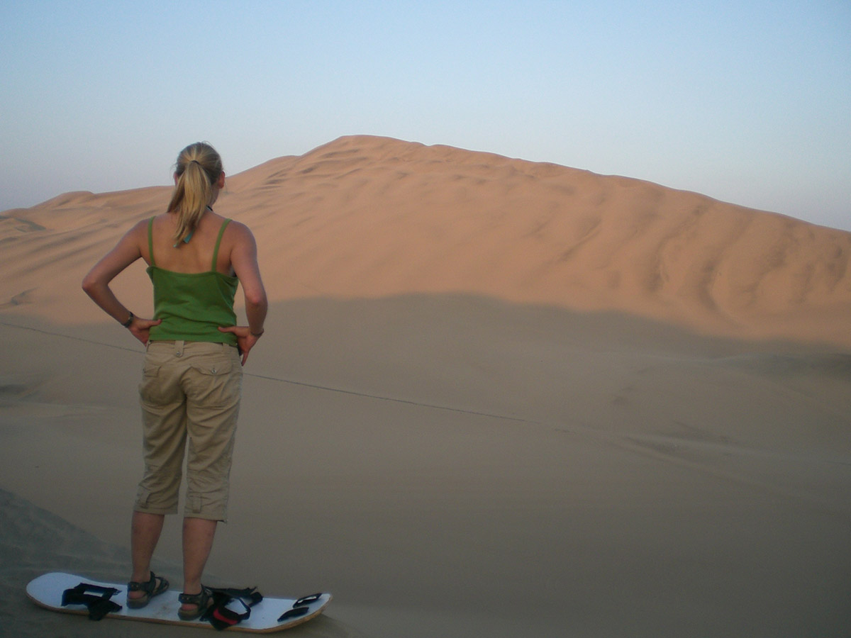 Woman with a sandboard at the sand dunes near Huacachina