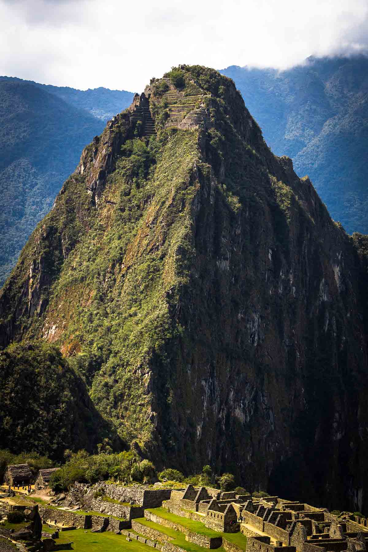 Huayna Picchu looms over the Machu Picchu ruins with the Moon Temple visible at the top.