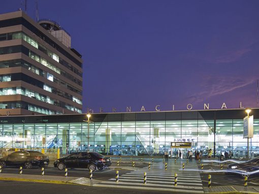 Front of the Lima airport with cars in front and purple night sky in background.