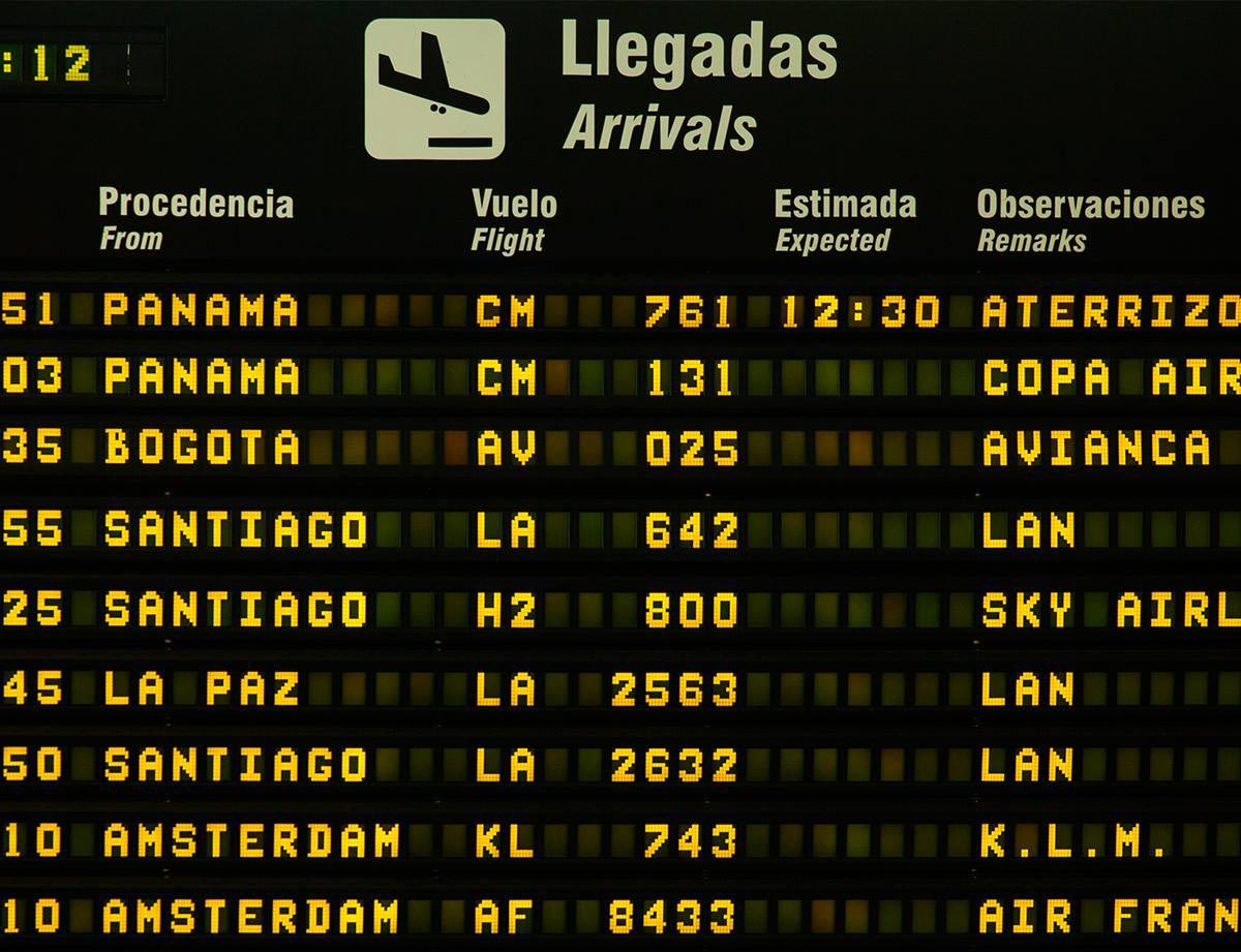Black board with white and yellow writing listing the arrival of international flights.