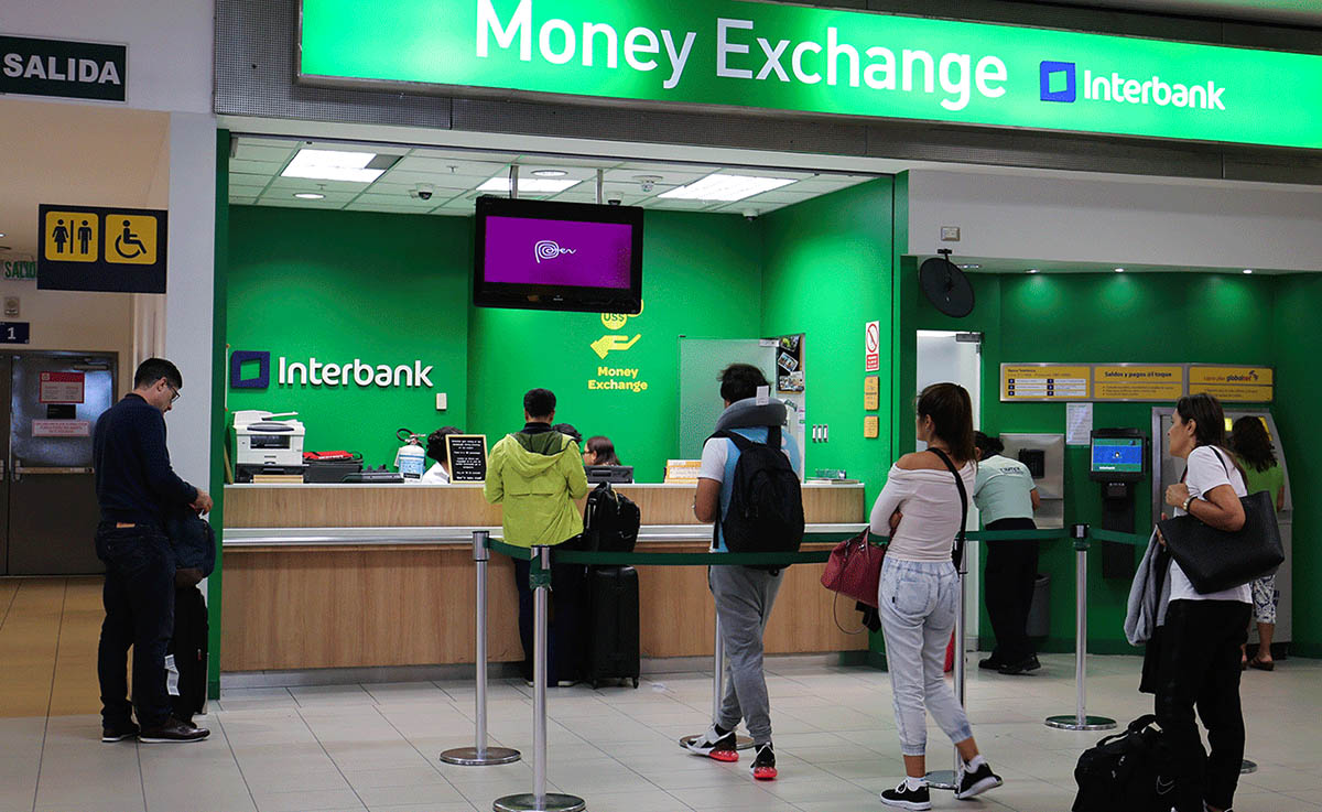 Several customers waiting in line for money exchange and ATMs at Interbank.