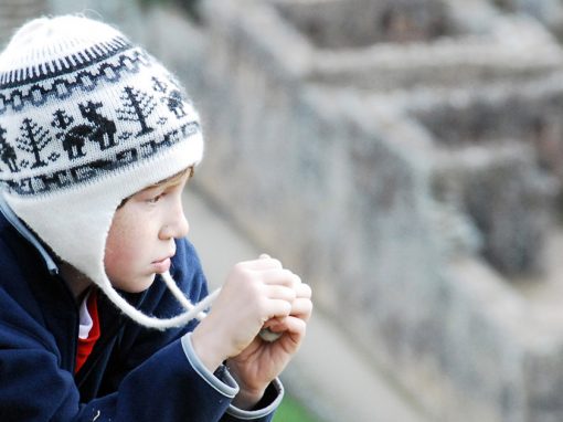 A child in a winter hat looks over the ruins of Machu Picchu.
