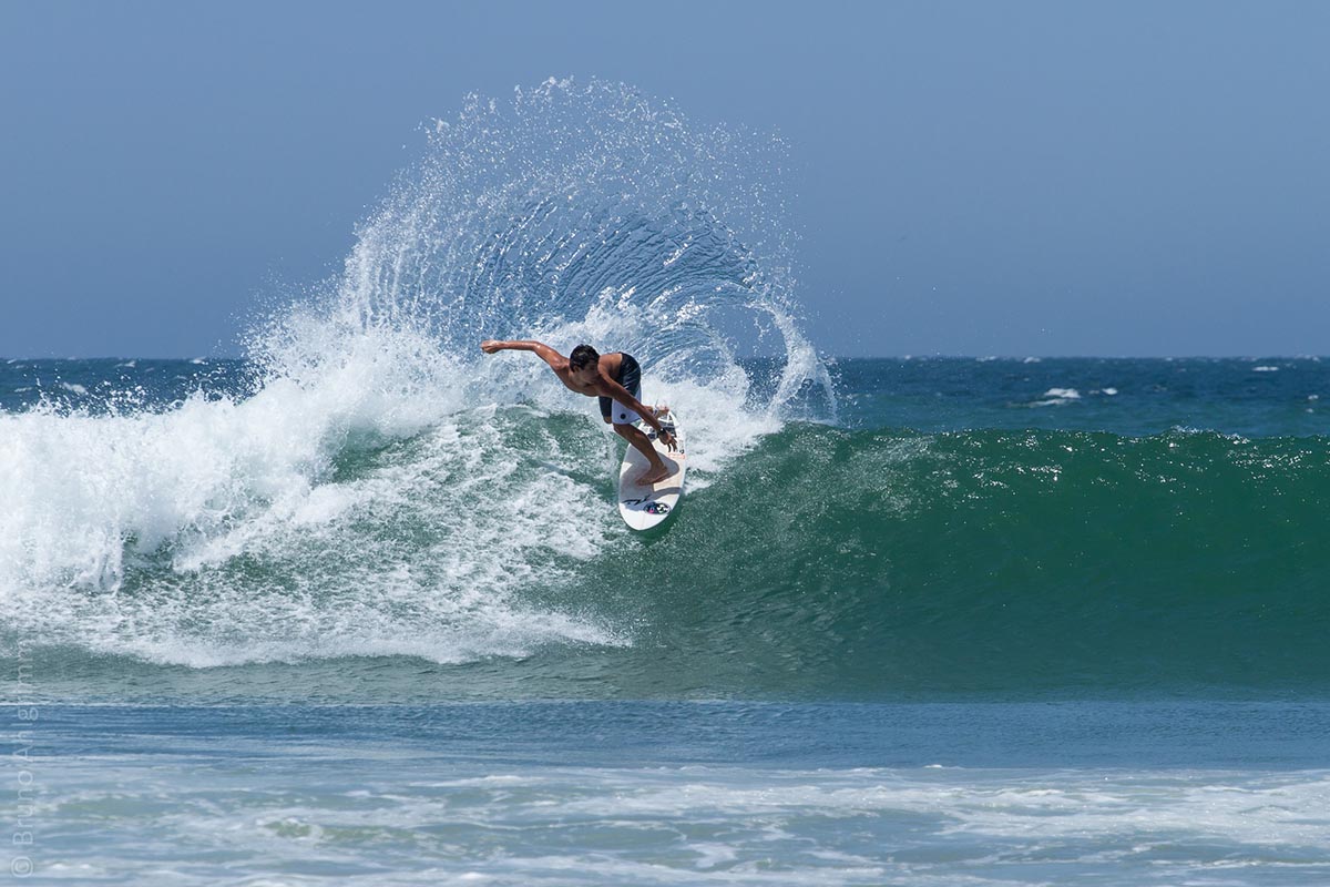 Surfer turning on a wave as it breaks behind him.