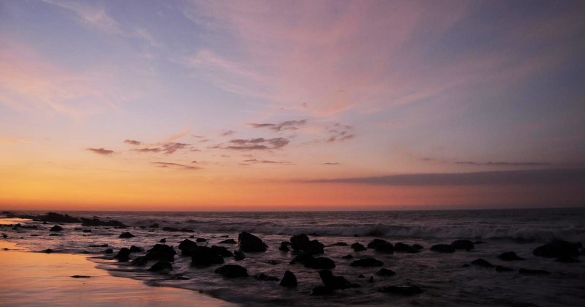 Sunset over the Pacific ocean dotted with lava rocks from Mancora beach in Northern Peru.