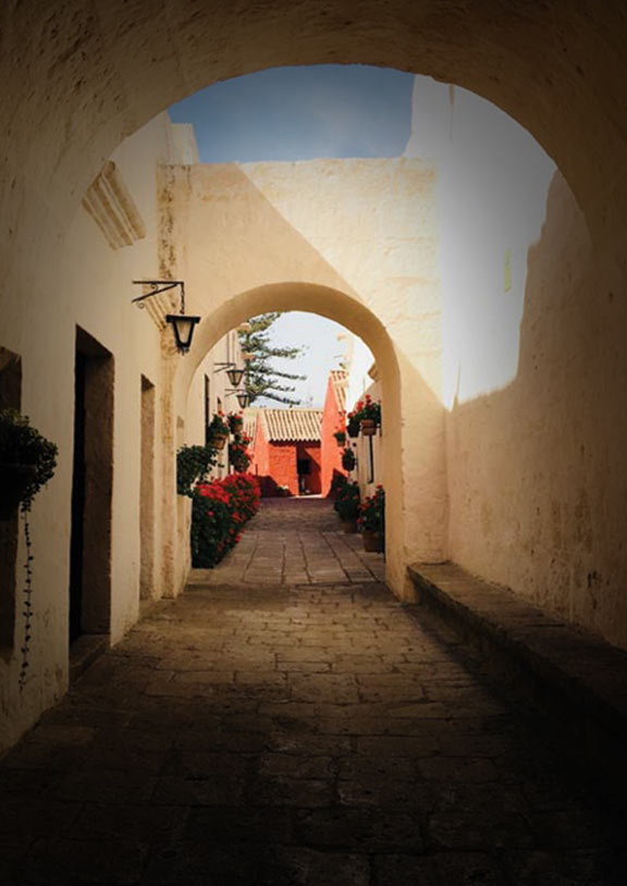 White arches above the entrance to Santa Catalina Monastery with a glimpse of red buildings inside