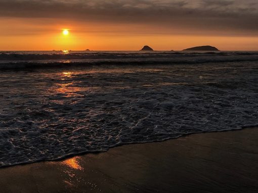 The setting sun turns the sky orange over the Los Pulpos beach on the Peruvian coast.