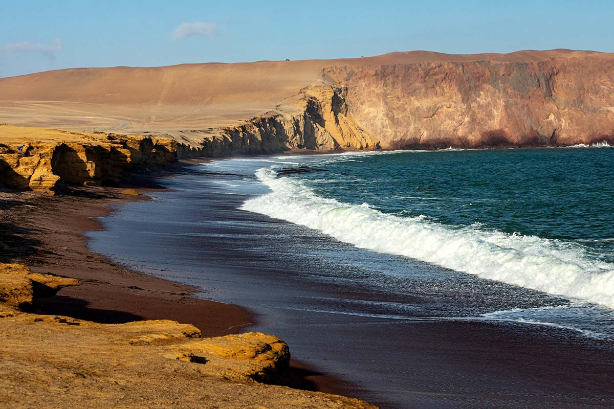 Yellow desert meets foaming blue ocean waves at Playa Roja in the Paracas National Reserve.