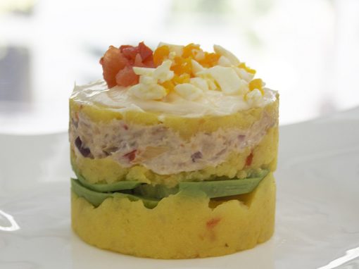 Causa rellena with avocado and creamy chicken topped with chopped egg and tomato.