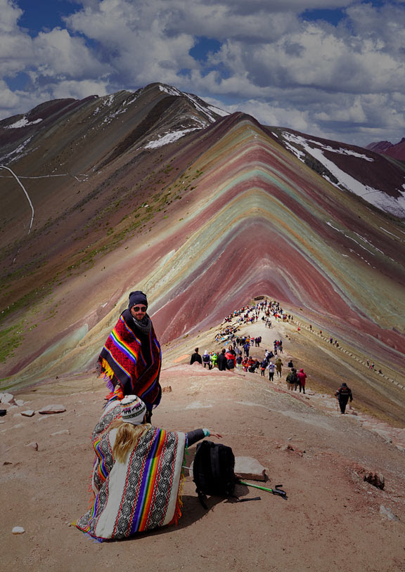 Visitors wearing traditional ponchos at the multi-colored Vinicunca Rainbow Mountain in Peru.