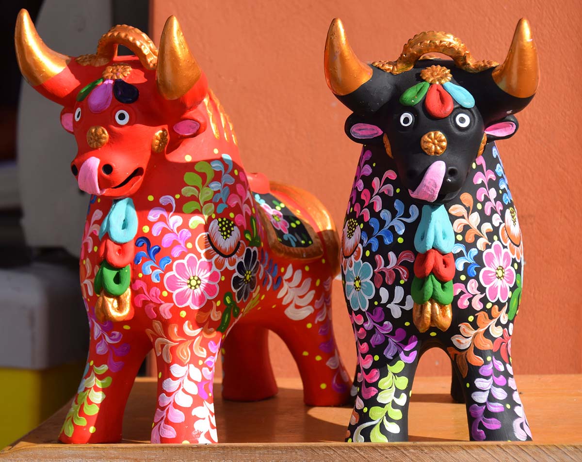 A red ceramic bull and a black one with brightly colored hand-painted flower designs.