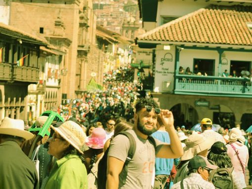 A tourist in Cusco lifting his sunglasses to look at something, amidst a crowd of people.