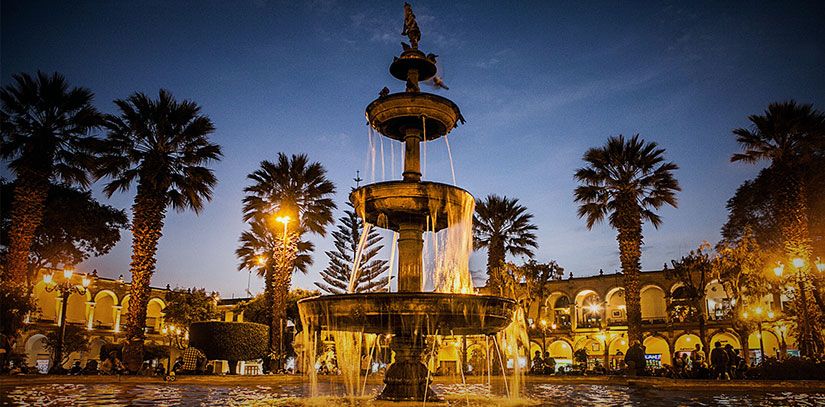 Fountain, buildings and palm trees at night in the Plaza de Armas of Arequipa, a popular destination of the 'white city'.